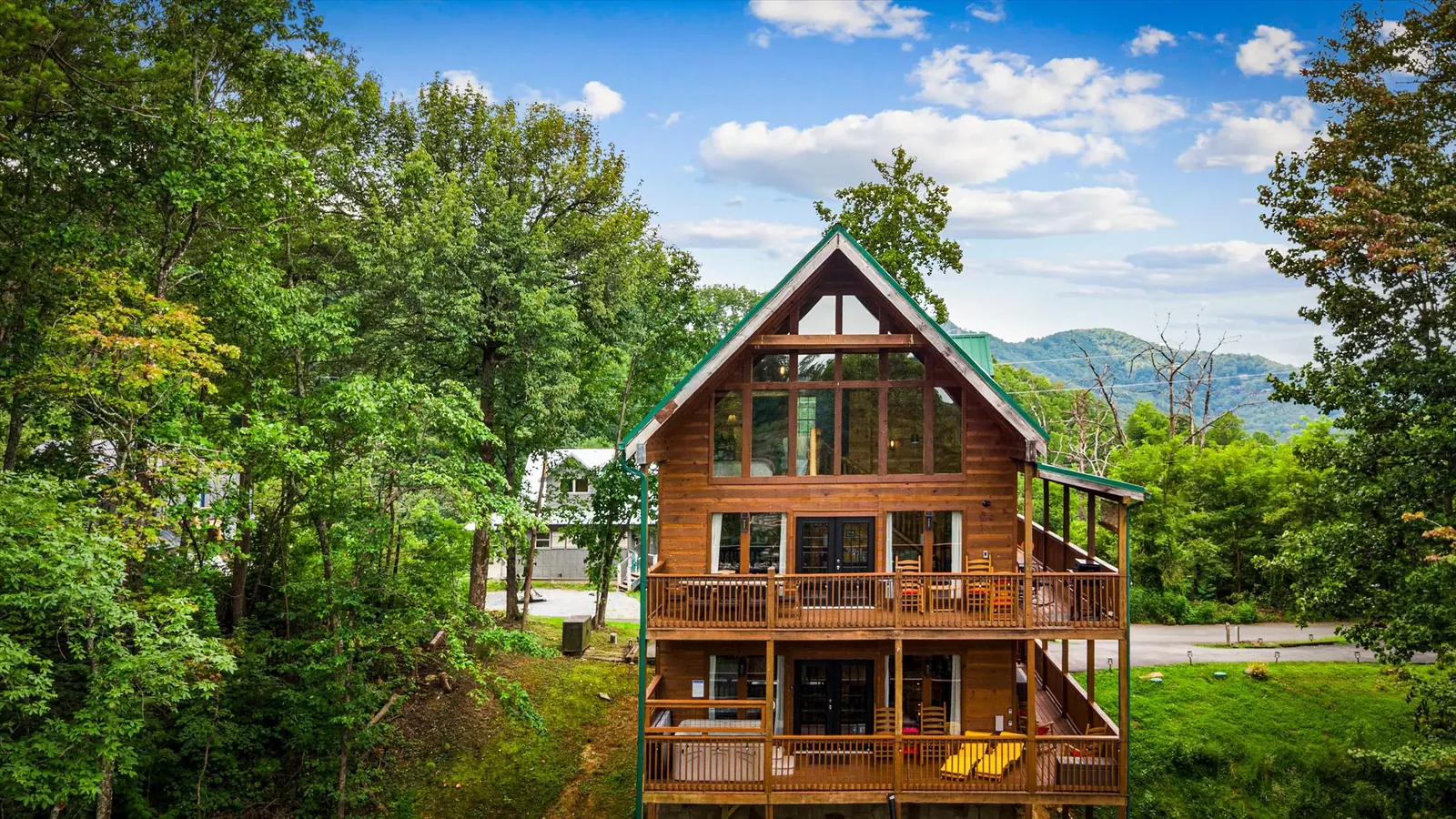 Front of Acorn Ridge cabin showing three levels of covered deck with mountains behind