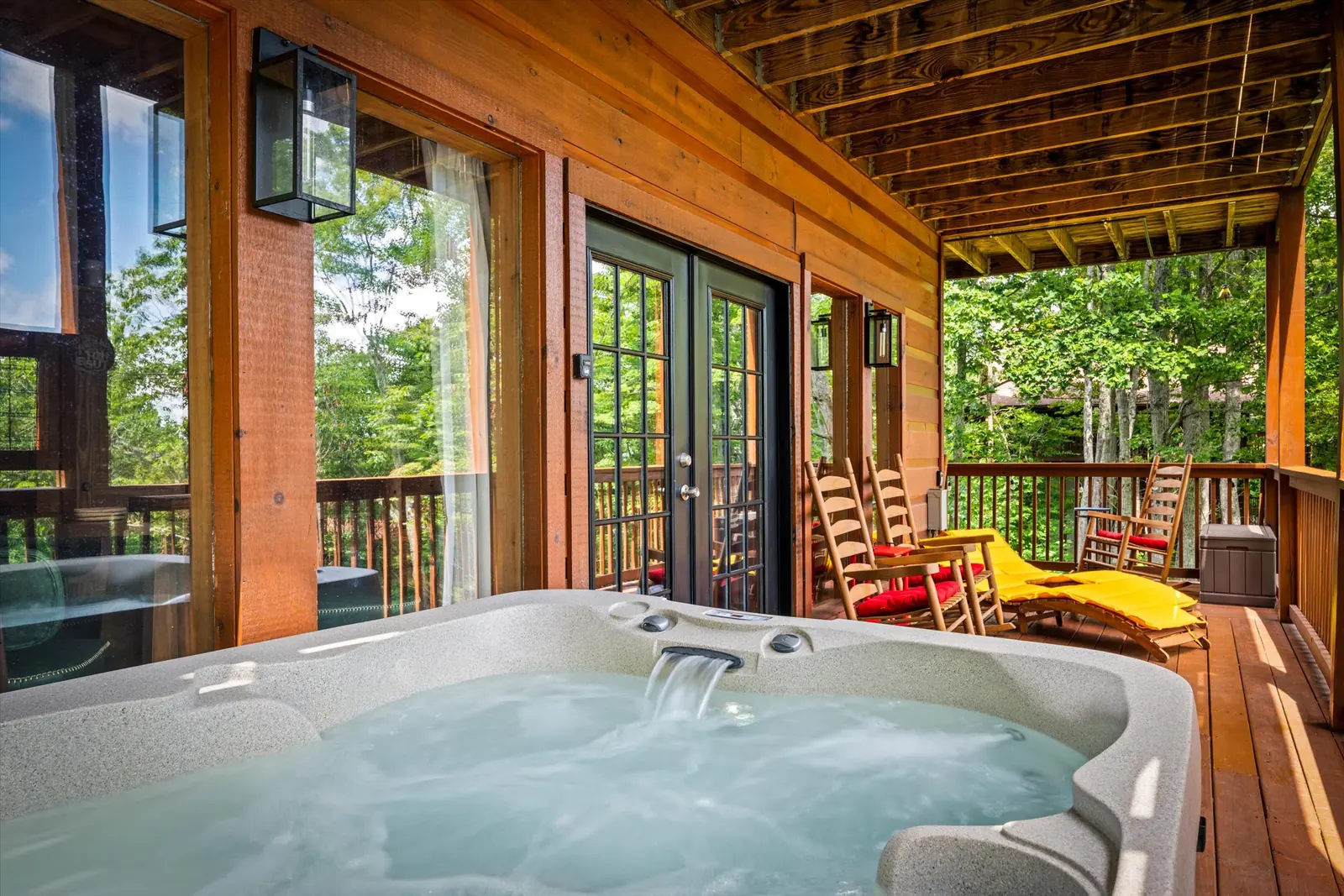 Hot tub beside rocking chairs on the covered deck at Acorn Ridge