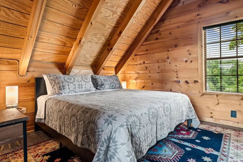 King bed in the top-floor master bedroom with exposed A-frame rafters